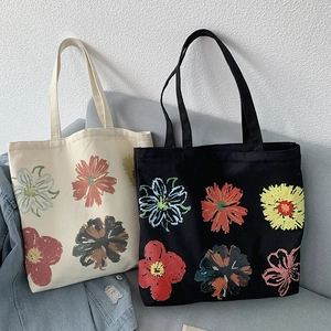 Close-up of canvas tote bag with floral print on a gray sofa next to denim jacket