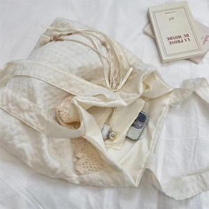 Detail view of large beige canvas tote bag showing inner zipper pocket and lace drawstring