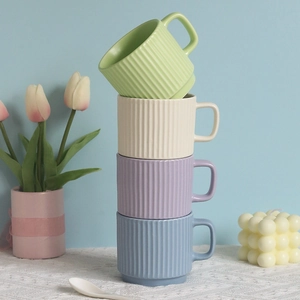 Stacked pastel ceramic mugs with vertical stripes in green, beige, purple and blue