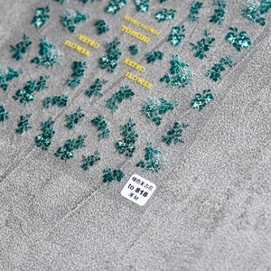 Close-up of retro green floral nail stickers on a thin adhesive sheet with detailed pattern