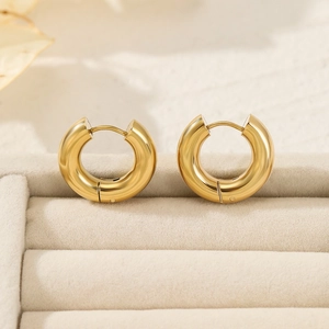 Close-up of polished gold hoop earrings in a beige velvet jewelry display box