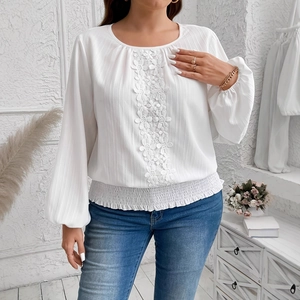 Detail of white chiffon top featuring floral lace embroidery and smocked elastic hem