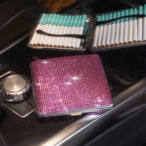 Detail view of pink rhinestone cigarette case inside a car showing functional storage space