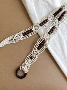 Macro detail of bohemian braided cotton waist chain with circular wood beads and ring