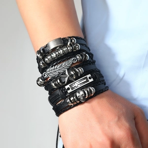Detail of layered punk leather bracelets with silver feather, skull and star charms