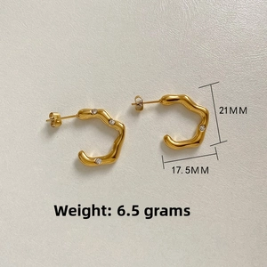 Detail view of gold wave C-shaped earrings with zircon inlay and product measurements