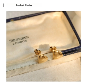 Detailed close-up of polished gold heart-shaped stud earrings on a vintage jewelry box