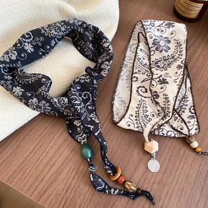 Close-up of bohemian scarves with paisley prints, wooden beads and metal pendants