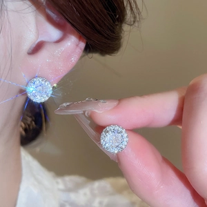 Macro shot of silver stud earring with brilliant round cubic zirconia and halo setting
