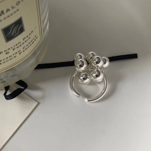 Detalle de anillo de racimo de cuentas plateadas en latón junto a una vela