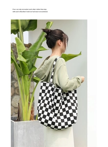 Close-up of black and white checkerboard canvas tote bag shown in a lifestyle setting
