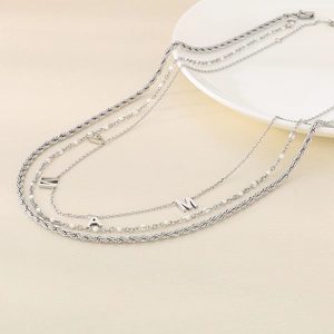 Detailed view of triple-layered silver steel MAMA letter pendant necklace on texture