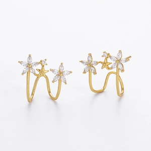 Dettaglio di orecchini a fiore dorati con zirconi marquise e piccoli elementi a stella