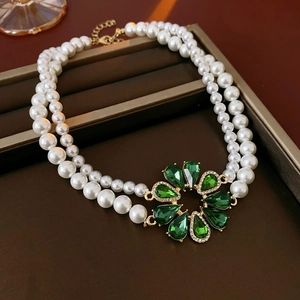 Dettaglio di una collana di perle a doppio strato con un grande ciondolo a fiore verde
