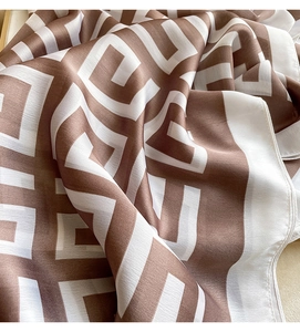 Detail of silk scarf showing geometric maze pattern and soft sheen of premium fabric
