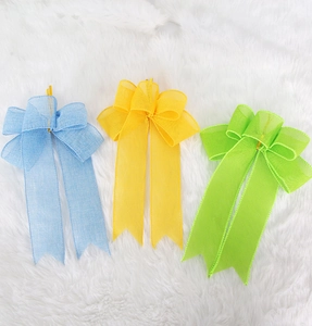 Detailed view of colorful linen Easter bows in blue, yellow, and green on white plush fabric