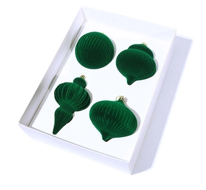 Detail of four emerald green velvet Christmas balls with assorted textures in a gift box