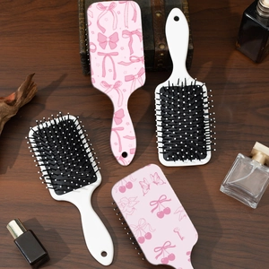 Spazzole per capelli con orsetto e fiocco rosa su un elegante tavolo in legno naturale