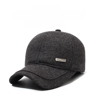 Detail of winter baseball cap with ear flaps and metal brand tag on dark grey wool fabric