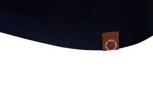 Detail of navy knit polo hem with ribbed texture and brown fashion leather label