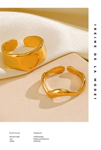 Detail of minimalist gold plated stainless steel smooth wide band and wavy open rings
