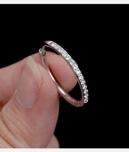 Dettaglio ravvicinato di un orecchino a cerchio in acciaio argento con zirconi trasparenti