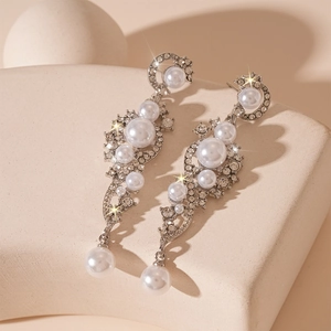 Detailed view of silver dangle earrings featuring faux pearls and sparkling rhinestones
