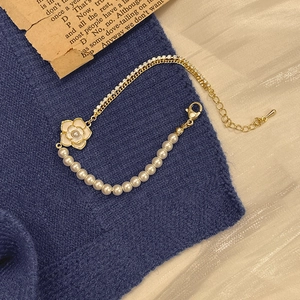 Close-up of camellia pearl bracelet with gold chain and crystals on blue fabric