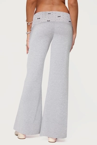 Detail view of grey flared pants featuring a black bow ornament and comfortable cotton blend