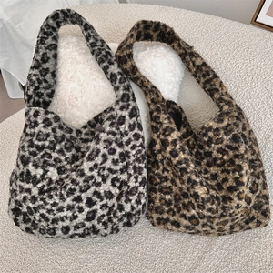 Detail of leopard print plush tote bags in black-grey and brown colors on soft fabric