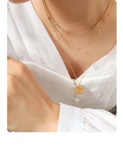 Detailed close-up of triple-layered gold necklaces with Good Luck round coin pendant