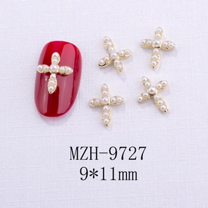 Dettaglio di ciondoli a croce dorata 9x11mm con perle bianche su unghie rosse