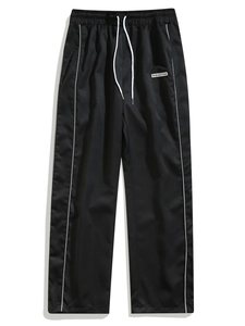Detail of men's woven joggers showing white side stripes and embroidered logo tag