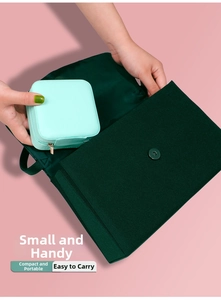 Mint green compact jewelry case being placed inside a green fabric travel bag