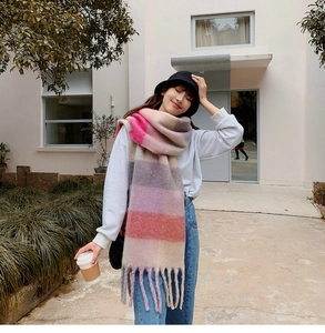 Detail of colorful plaid scarf featuring soft pink and lilac blocks with long tassels