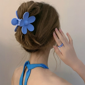 Detail showing blue flower hair claw clip and matching bead ring on model's hair