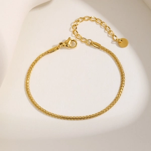 Close-up of 18K gold braided stainless steel necklace with lobster clasp and round tag