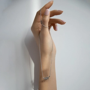 Detail of a minimalist 925 silver leaf pendant bracelet held by a hand on a white background