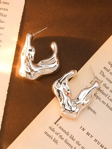 Artistic close-up of C-shaped irregular liquid metal flower earrings in shiny silver