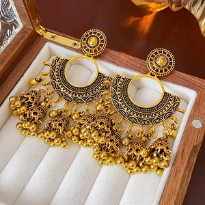 Detailed macro view of vintage golden Jhumka earrings with bells in a wooden jewelry box