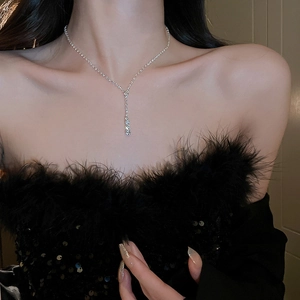 Détail du collier pampille en Y argenté avec strass brillants porté par un mannequin