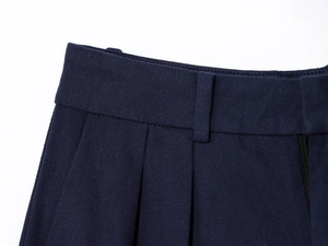 Detailed view of pleated trousers' waistline with belt loops in navy blue twill fabric