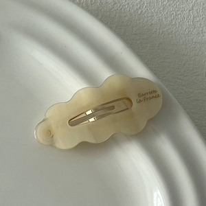 Vue détaillée d'une barrette à cheveux ondulée en acétate marbré avec clip doré