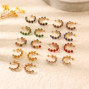 Dettaglio di orecchini in acciaio dorato con zirconi quadrati colorati assortiti
