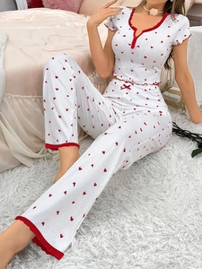 Detail of white rib-knit pajamas with red heart prints and delicate red lace trimming