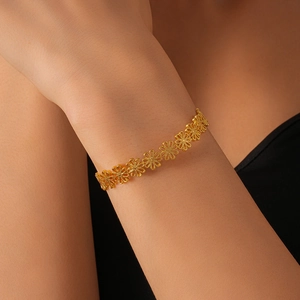 Detailed close-up of golden hollow flower pattern bracelet on model wrist