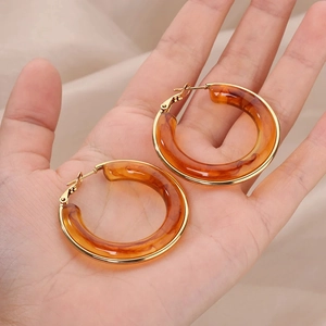 Boucles d'oreilles créoles rétro en résine ambre et cadre doré sur tissu beige