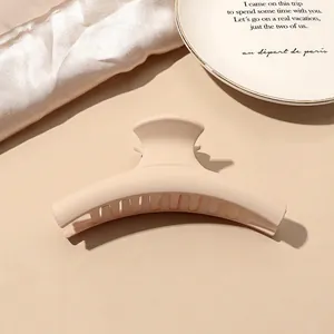 Matte beige large hair claw clip for thick hair shown on a minimalist prop background