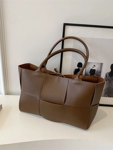 Brown woven tote bag with dual handles and drawstring closure against a white background