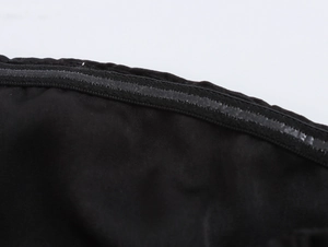 Dettaglio ravvicinato della striscia antiscivolo in silicone sull'abito di raso nero
